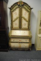 Full front view of the secretary desk showing floral painted bombe shape and drop front writing surface closed.