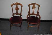 Pair of two Victorian walnut side chairs with carved backrests and burgundy velvet seats, placed side by side.