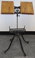Full view of dictionary stand showing wide spider cast iron legs, steel adjustable shaft, and oak cradle book support.