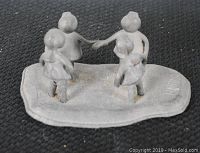 Top angle view of the pewter sculpture showing four children holding hands and the irregular base.