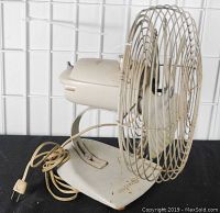 Photo front-left side of mid-century General Electric 10 inch oscillating fan, showing power cord, base, motor housing, and blade cage with some surface rust and wear.