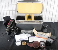 Full view of the Canon A-1 camera, two lenses, manuals, light meter, flash and the open Samsonite case showing fitted interior.