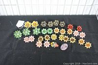 Photo showing a variety of vintage metal flower curtain tieback pins in multiple colors, mostly pin backs with some screw backs visible.