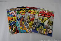 Four Luke Cage Power Man vintage comic books displayed fanned out showing cover art and condition.
