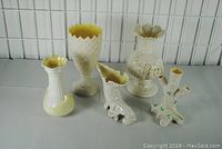 Group photo of all five Irish Belleek porcelain vases showing varied rim styles and decorative designs, including applied floral applique with chips