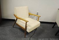 Side view of mid-century lounge armchair with white vinyl upholstery and wooden frame showing condition and structure.
