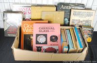 Box containing multiple books about antiques, collectibles, baseball cards, crystals, and carnival glass.