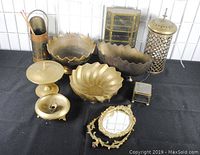 Collection of brass bowls, decorative shaving mirror, covered candy dish, small drawer chest, candle holders, small box, and matchstick holder.