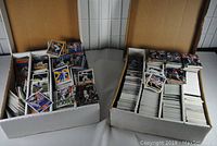 Two large boxes filled with loose baseball and basketball sports cards.