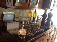 Photo of silverware laid out showing spoons in cases, various knives and forks, and large decorative bottles at the back
