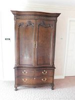 Front view of closed armoire showing carved doors, brass hardware and lower drawers