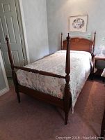 Wooden single four-poster bed set up in bedroom, showing headboard, footboard, and posts