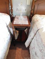 Side table with wood carved legs and marble top between two beds