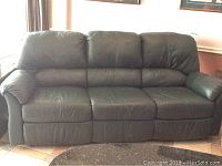 Full view of green leather sofa showing three cushions and two reclining sections at the ends