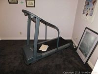 Full side view of the PaceMaster treadmill in a carpeted room, showing its size and design.