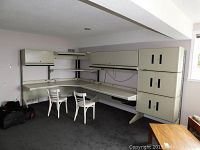 Full view of L-shaped modular office desk system with hutch and multiple cabinets in beige metal.