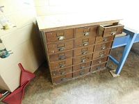 Front view of wooden cabinet showing multi-drawer antique storage base and replaced top with paint splatters and wear