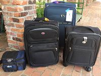 Four-piece luggage set with three wheeled suitcases and one Thermos lunch bag, all shown on outdoor brick surface.