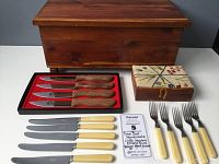 Photo showing the closed cedar wooden box with crewel embroidery on the lid, OVB cutlery with Bakelite handles, and four Walco steak knives in a tray.