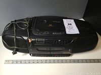 Full view of black Sony CFD-110 CD radio cassette player with power cord wrapped on top. Shows CD lid, buttons, and speakers.