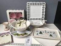 Photo showing entire lot contents including heart ramekins, white open loop plate, divided serving tray with snowman, bunny cake pedestal, Christmas tree tray, and smaller ceramic pieces.