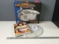 Lot contents showing 12 inch Calphalon pan box, Rachel Ray cookbook, and round marble slab on a surface.