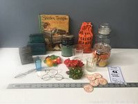 Wide view of the full collection of vintage small collectibles including storybook, tins, glass, ceramics, eyeglasses, tokens and more