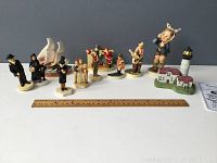 Full view of all 11 miniature collectibles including nine Sebastian Miniatures, one Hummel figurine and one Spoontiques lighthouse, with a ruler for scale.