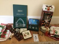 Photo of full lot showing boxed Waterford crystal figurines, holiday linens, sleigh bells, coasters and other Christmas items.