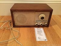 Full front view of vintage KLH Model 21 radio showing wooden case, fabric speaker cover, and control panel with knobs and tuning dial.
