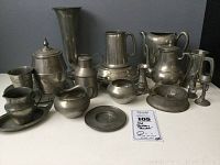 Photo showing full collection of vintage pewter pieces arranged on a table including pitchers, bowls, mugs, candle holders.