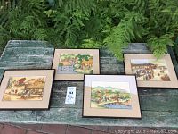 Photo showing all four framed paintings of the four seasons arranged on a wooden surface outdoors.
