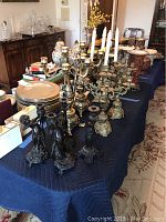 Overall view of table with assortment of brass and iron candlesticks