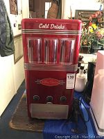 Front view of red Nostalgia Electrics Retro Series soda dispenser with three dispensing buttons and branding visible.
