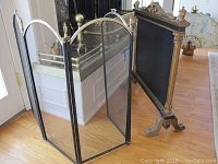 Three-panel brass and black metal mesh folding fireplace screen with ball finials