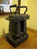 Front view of one antique kerosene iron showing rectangular base and handle