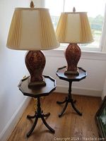 Pair of matching lamps placed on matching wooden side tables near window.