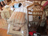 Overview: wood valet stand with comforter set, decorative pillows and red slippers on floral bed