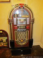 Front view of the complete jukebox showing wood veneer cabinet, chrome accents, light tubes and base