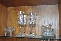 Photo showing four tall crystal champagne glasses, one sugar bowl with ornamental feet, and a tray with cream and sugar containers.