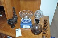 Shot of the full set featuring the decanter, shot glasses, clear cut glass bowl and plate, and dark glass bowl and bird figurine