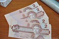 Front side view of four Canadian 2 dollar bills from 1986, each showing Queen Elizabeth II's portrait and denomination markings.