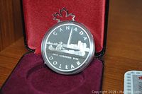 Front side of the coin with 'CANADA DOLLAR' text and depiction of a canoe with a paddler in front of Toronto skyline and CN Tower, dated 1834-1984.
