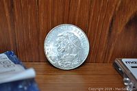 Photo of one side of a Mexican 25 centavos coin showing the Mexican national emblem with eagle and snake.