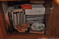 Photo of shelf with stacked books, magazines, cedar blocks on a tray, and a glass vase.