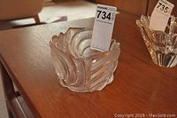 Textured square-shaped crystal vase with swirled pattern and a lot tag placed inside on a wooden table next to a clear crystal bowl.