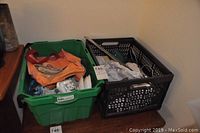 Two large bins with assorted kitchenware items, including cups, plates, glassware, and utensils, packed with paper.