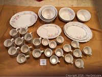 Full view of the 38-piece Pfaltzgraff Rose dinnerware set showing plates, bowls, and cups arranged on fabric