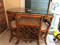 Rattan table and two chairs nested together under a clear glass top
