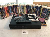 Sony VHS VCR in black with remote and cables, framed by Disney VHS movie cases arranged behind